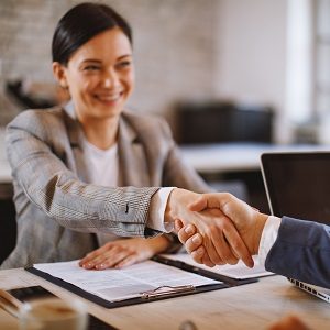 Businesswoman and businessman make a deal and shake hands selective focus on hands