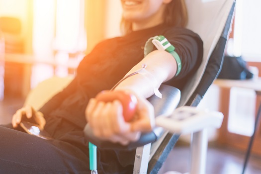 Junge Frau mit herzförmigen Ball in der Hand beim Blutspenden