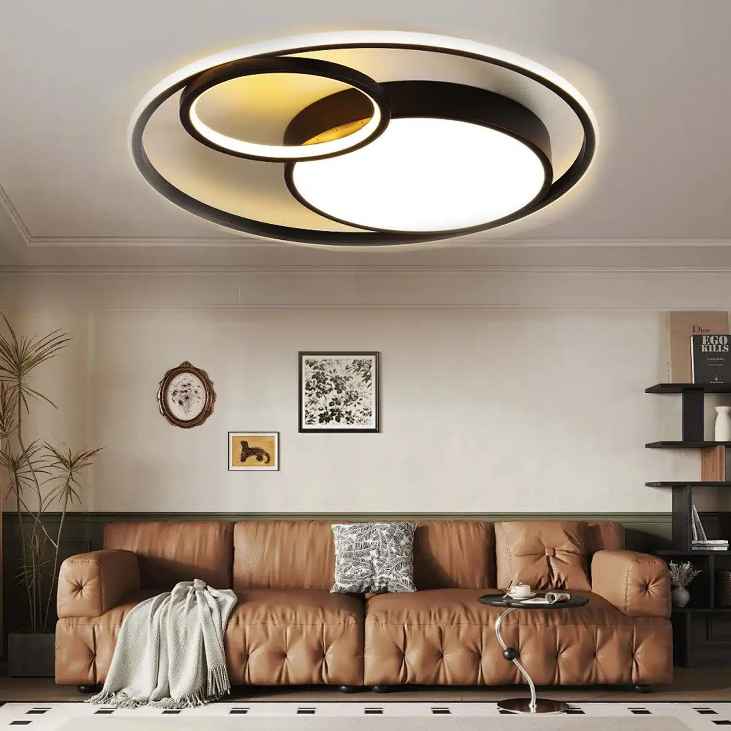 Moderne Deckenleuchte mit zwei ineinandergreifenden Ringen, die warmes Licht ausstrahlen, in einem stilvollen Wohnzimmer über einem braunen Ledersofa. Der Raum ist minimalistisch eingerichtet mit Kunstwerken an der Wand und einem Beistelltisch.