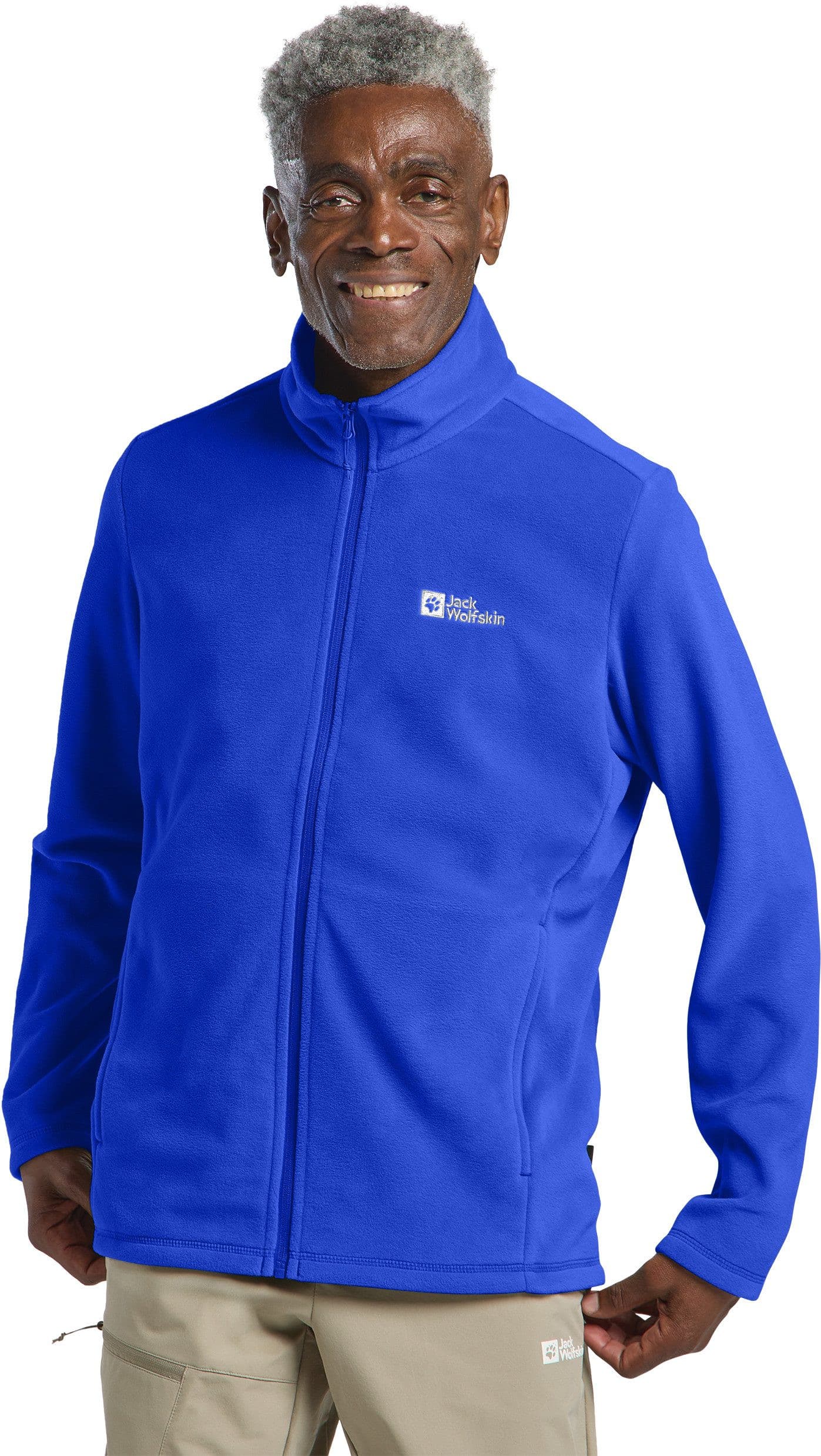 Ein Mann trägt eine leuchtend blaue Jack Wolfskin Fleecejacke mit Reißverschluss. Er lächelt in die Kamera und steht vor einem neutralen Hintergrund.