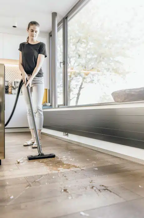 Frau saugt mit ihrem Kärcher WD 2 Plus V-12/4/18 C Nass- & Trockensauger den verdreckten und nassen Boden auf.