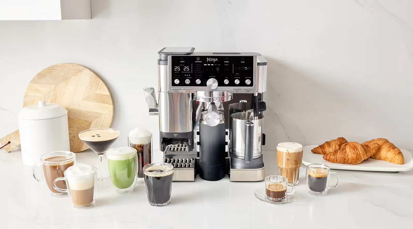 Zu sehen ist die Ninja Luxe Café Pro Kaffeemaschine - ES701EU, umgeben von vielen Kaffeespezialitäten, Küchenhelfern und Lebensmitteln.