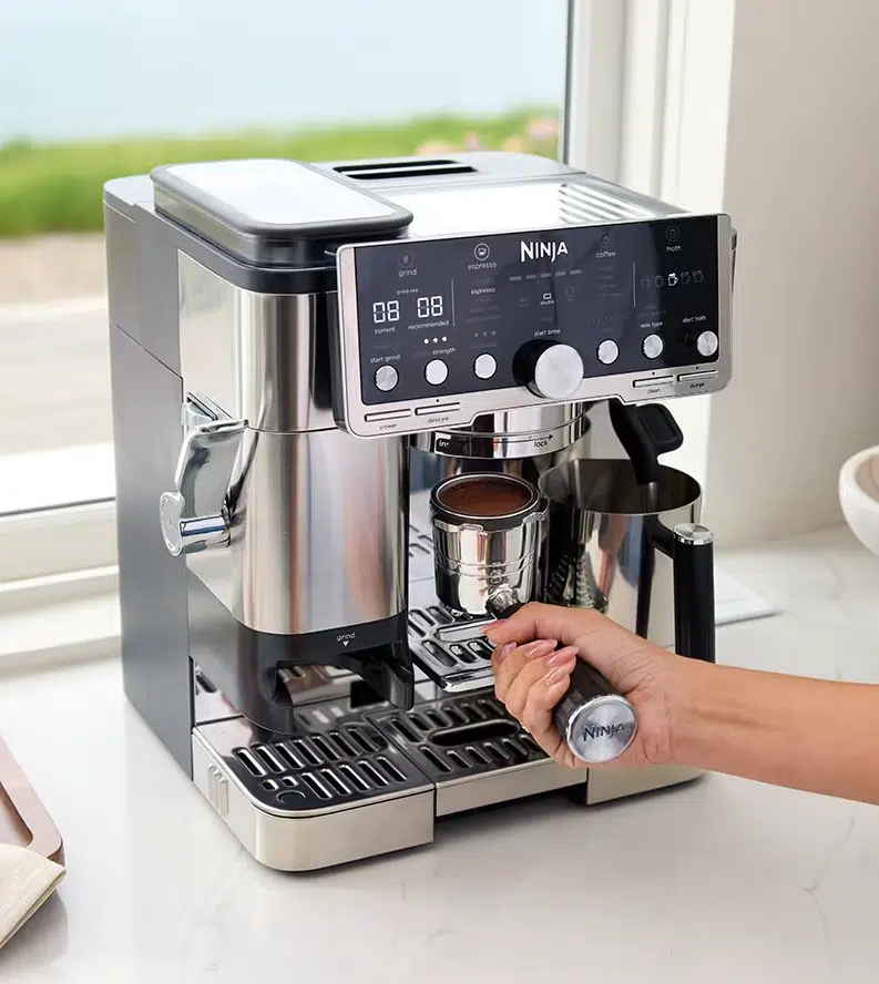 Zu sehen ist die Ninja Luxe Café Pro Kaffeemaschine ES701EU und wie dort der Siebträger mit gemahlenem Kaffee eingesetzt wird.