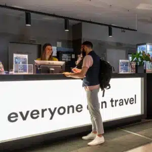 Mann, der in einem a&o Hotel an der Rezeption steht und mit der Rezeptionistin spricht