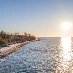 winterliche-ruhe-am-strand-bei-torfbruecke-verschneite-waelder-glitzernde-ostseewellen
