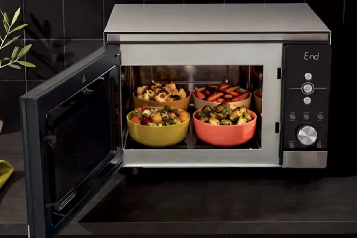 Ninja Crispi Microwave mit geöffneter Tür: Der Innenraum ohne Drehteller beherbergt vier Schüsseln mit verschiedenen Gemüsen